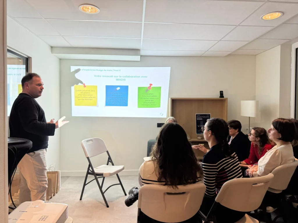 Photo d'une personne debout faisant une pr&eacute;sentation &agrave; un groupe de personnes assises durant l'IMA'Club Atlantique 2025